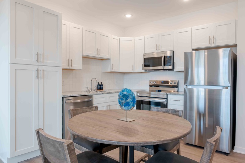 a kitchen with white cabinets stainless steel appliances and a table with chairs